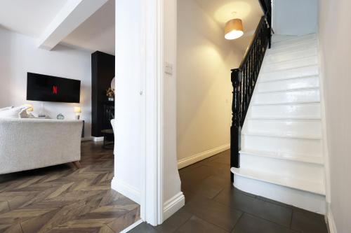a staircase in a living room with white walls and wood floors at Spacious 3 Bedroom Home in Heart Of Pontypool With Parking - By EKLIVING LUXE Short Lets & Serviced Accommodation in Griffithstown