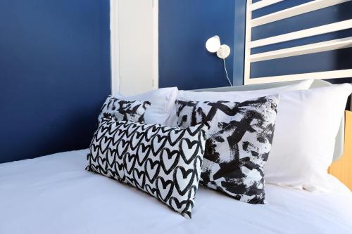 a bed with black and white pillows on it at Spacious 3 Bedroom Home in Heart Of Pontypool With Parking - By EKLIVING LUXE Short Lets & Serviced Accommodation in Griffithstown