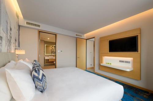 a bedroom with a white bed and a flat screen tv at OZO George Town Penang in George Town