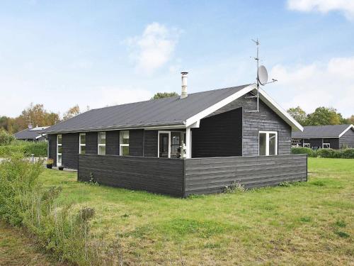 a black house with a white roof on a field at 6 person holiday home in Hals-By Traum in Hals