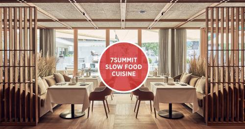 a sign in a restaurant with tables and chairs at Falkensteiner Hotel Kronplatz - The Leading Hotels of the World in Brunico