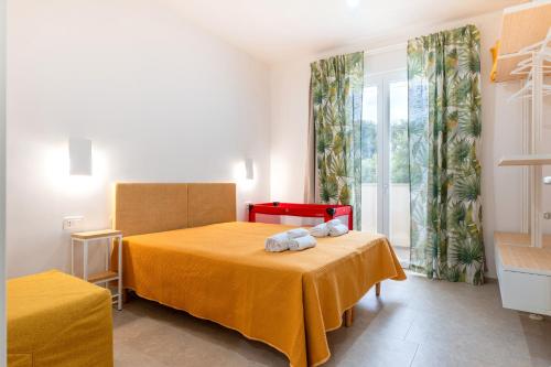 a bedroom with a bed with a yellow blanket and a window at Helianthus in Cisternino
