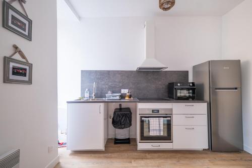a kitchen with white cabinets and a refrigerator at Confort & circuit - Séjour idéal au Mans in Le Mans