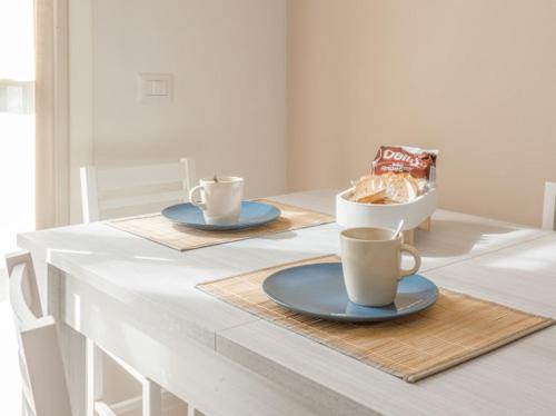 a table with two cups of coffee and a bowl of bread at Nour Apartments - Castramajora Alloggi in Casalmaggiore