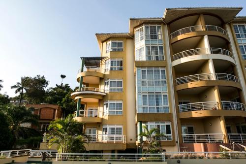 a tall yellow building with balconies and trees at Enkombe Place in Kampala