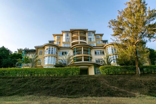 a large yellow building with bushes in front of it at Enkombe Place in Kampala