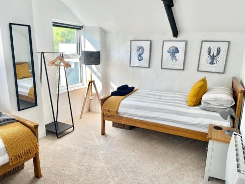 ein Schlafzimmer mit einem Bett mit gelben Kissen und einem Spiegel in der Unterkunft Finest Retreats - Porth Cottage in Newquay