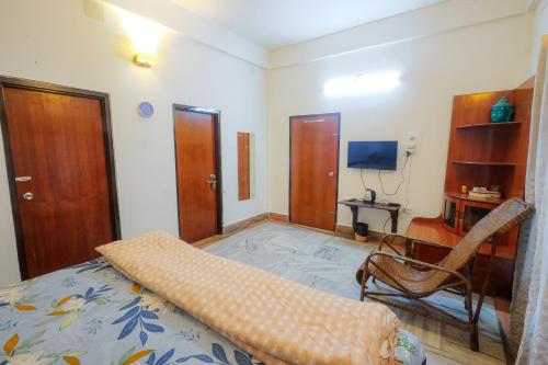 a bedroom with a bed and a chair and a television at Bhaskar Homestay - The Bungalow in Dibrugarh