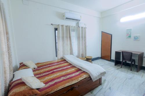 a bedroom with a bed and a desk in it at Bhaskar Homestay - The Bungalow in Dibrugarh
