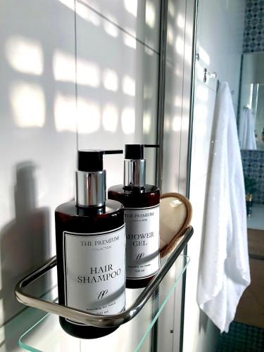 two bottles of hair shampoo on a glass shelf in a bathroom at Authentic apartments with jacuzzi and Two-level central Haifa in Haifa