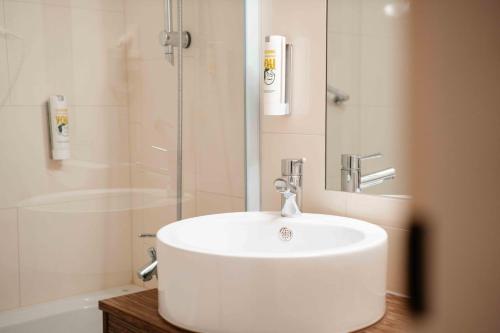 a bathroom with a white sink and a shower at SLEEEP Hotel Vösendorf in Vösendorf