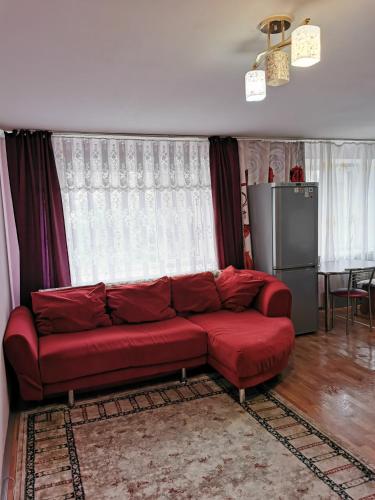 a red couch in a living room with windows at 2 комн квартира в центре по Пушкина in Kostanay