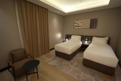 a hotel room with two beds and a chair at Snood Al Narjis Hotel in Riyadh