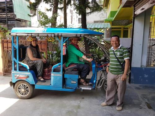 two men and a woman sitting in a golf cart at Bhaskar Homestay - The Bungalow in Dibrugarh