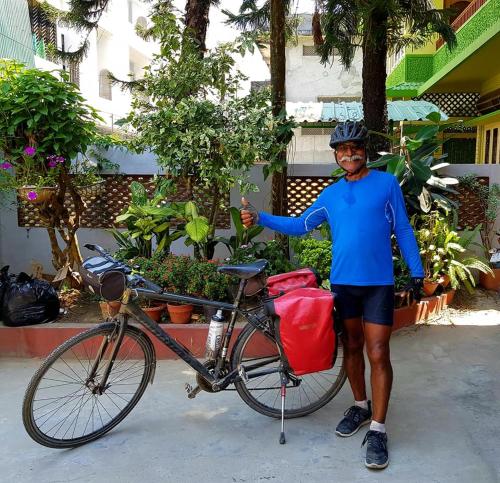 a man is standing next to a bike at Bhaskar Homestay - The Bungalow in Dibrugarh