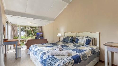 a bedroom with a blue and white bed and a window at Emerald Cove in Shelly Beach