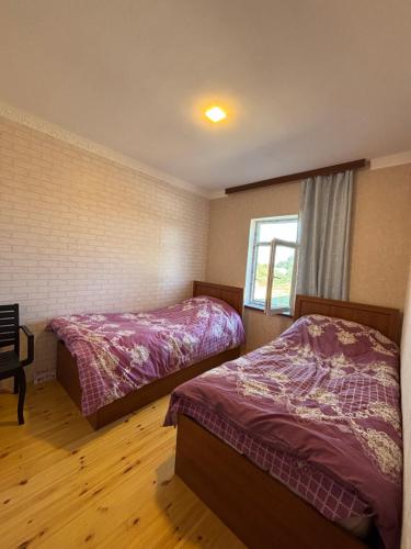 a bedroom with two beds and a window at İvanovka House in İsmayıllı