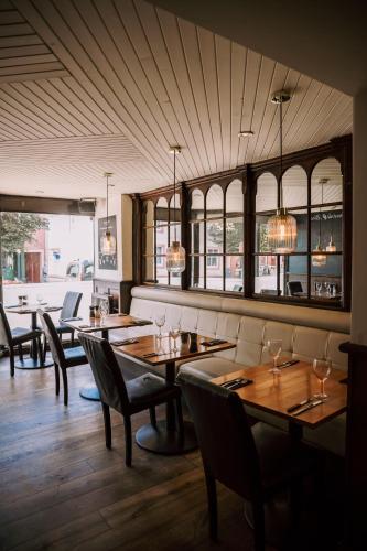 a restaurant with wooden tables and chairs and windows at Allerdale Court Hotel in Cockermouth