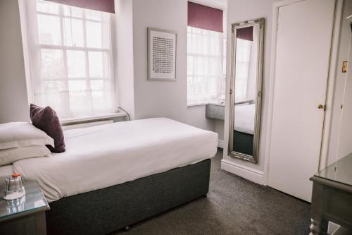 a white bedroom with a bed and a mirror at Allerdale Court Hotel in Cockermouth