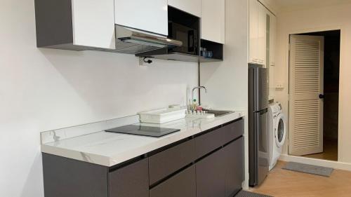 Una cocina blanca con fregadero y lavadora. en Modern 59m Sukhumvit 1BR - 31st Floor Pool - Gym, en Makkasan