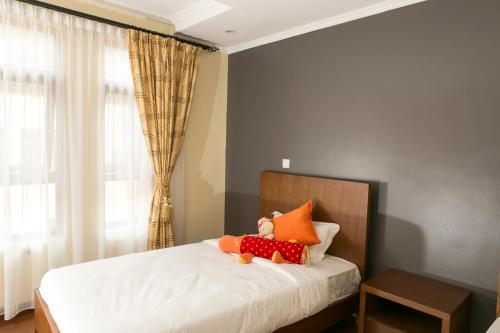 a bedroom with a bed with a teddy bear on it at Enkombe Place in Kampala