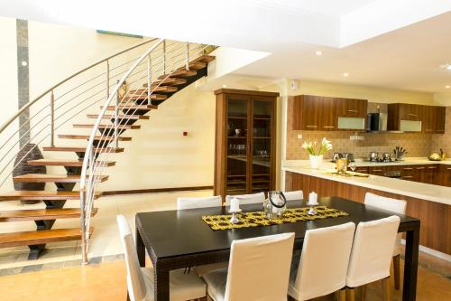 a kitchen and dining room with a table and a staircase at Enkombe Place in Kampala