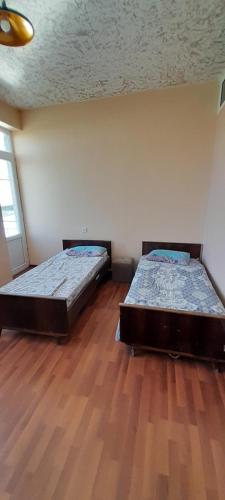 two beds in a room with a wooden floor at Avan Guesthouse 3 in Yerevan
