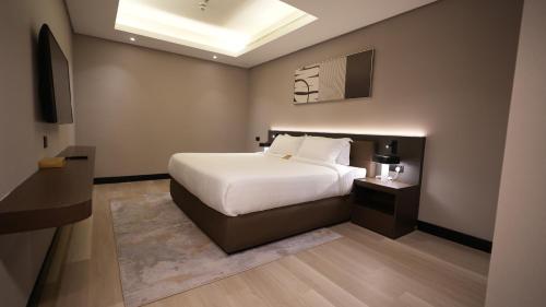 a bedroom with a white bed and a television at Snood Al Narjis Hotel in Riyadh