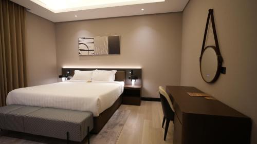 a bedroom with a bed and a table and a mirror at Snood Al Narjis Hotel in Riyadh