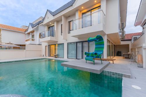 a green chair sitting next to a swimming pool at TML urban 4 bedroom 6 bathroom villa private KTV room and swimming pool in Pattaya South