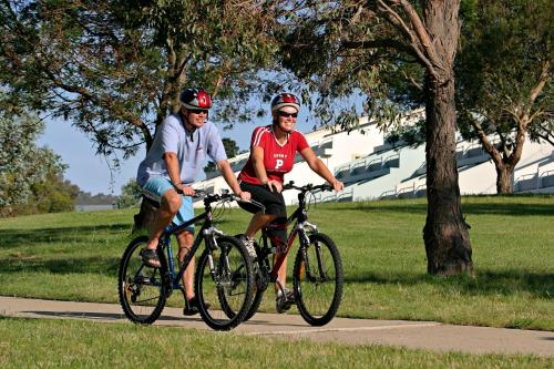 two men riding bikes on a path in a park at Horizons Lake Jindabyne in Jindabyne
