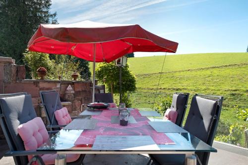 a table with a red umbrella and chairs at Grundhäusle Gütenbach in Gütenbach
