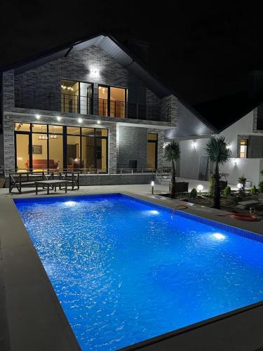 a large blue swimming pool in front of a house at VM Villa in Baku