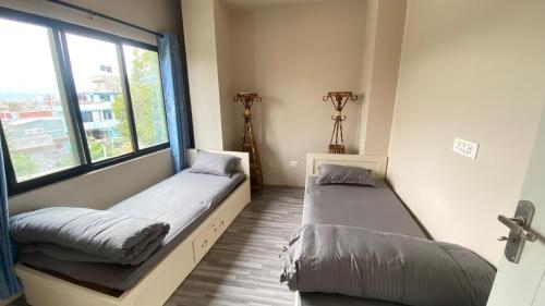two beds in a room with a window at Verve Nepal's Hostel in Kathmandu