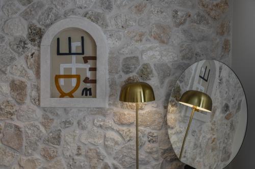 a mirror and a lamp next to a stone wall at Santa Boka in Perast