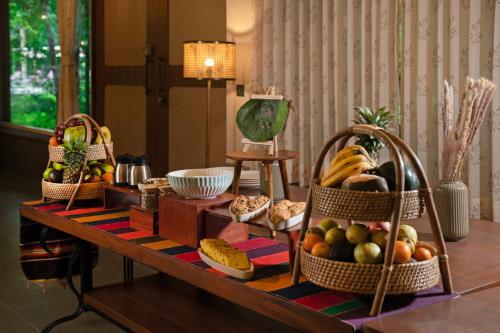 Brij Sone Bagh, Bandhavgarh - A Luxury Jungle Retreat في Tāla: طاولة عليها سلال فواكه وخبز