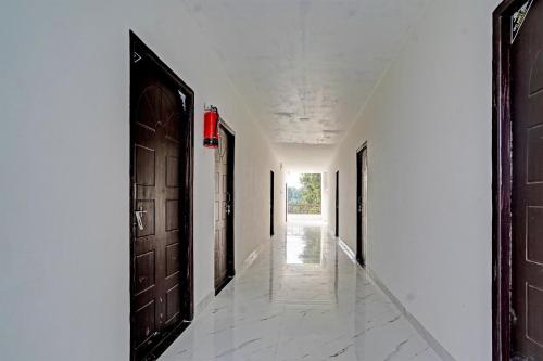 Hotel O Hira Royal Palace And Lawn في لاكناو: ممر فارغ بأبواب سوداء وجدران بيضاء