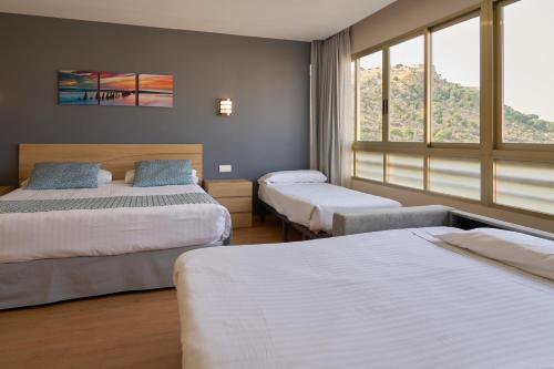 a bedroom with two beds and two windows at Hotel Maya Alicante in Alicante