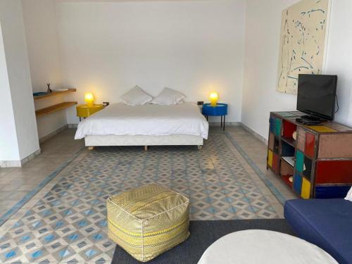 a bedroom with a bed and a television and a ottoman at Villa blanche in Mirleft
