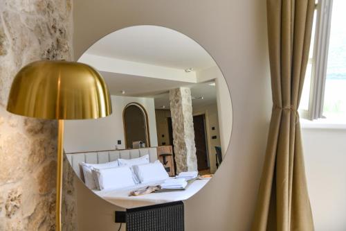 a mirror in a room with a bed and a lamp at Santa Boka in Perast
