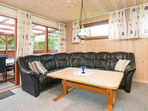 a black leather couch in a living room with a coffee table at 4 person holiday home in Juelsminde-By Traum in Snaptun