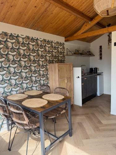 a table and chairs in a room with a stone wall at 't Hoevehuisje in Beverwijk