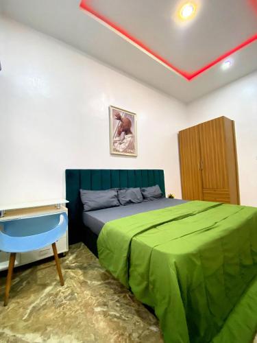 a bedroom with a green bed and a desk at Kstephen Apartment in Lekki