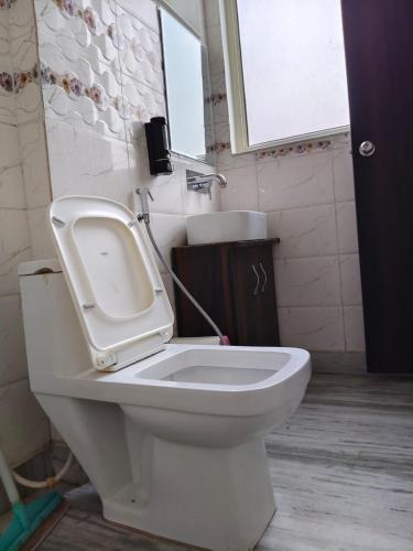 a bathroom with a toilet with a sink and a window at Hotel Yoga Stay Rishikesh in Rishīkesh
