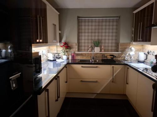 a kitchen with white cabinets and a sink at Remarkable 2-Bed House in Walesby Nottinghamshire in Elkesley