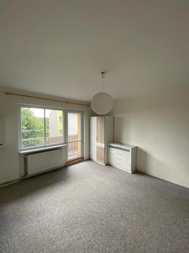 an empty living room with a window and a dresser at Tisá byt in Ústí nad Labem