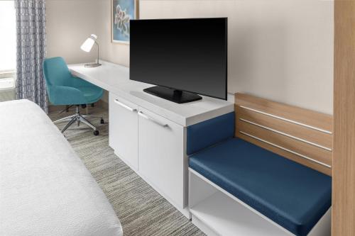 a bedroom with a desk with a tv and a chair at Hilton Garden Inn Queens JFK in Queens