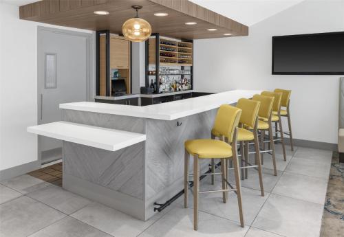 a bar with a row of yellow bar stools at Hilton Garden Inn Queens JFK in Queens