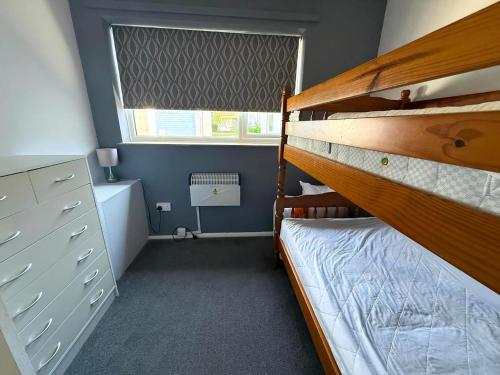 ein Schlafzimmer mit Etagenbett und Fenster in der Unterkunft Dog Friendly Chalet With Outdoor Seating At Broadland Park And Marina Ref 12050B in Lowestoft