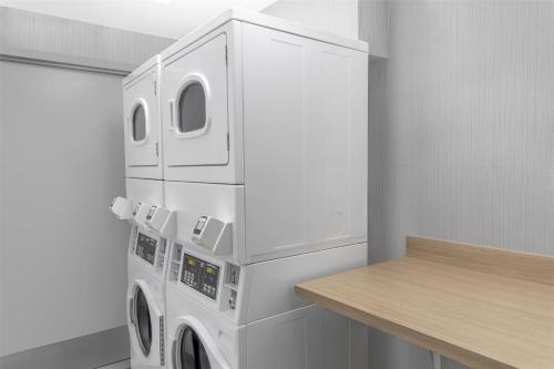 a white laundry room with a washer and dryer at Hilton Garden Inn Queens JFK in Queens
